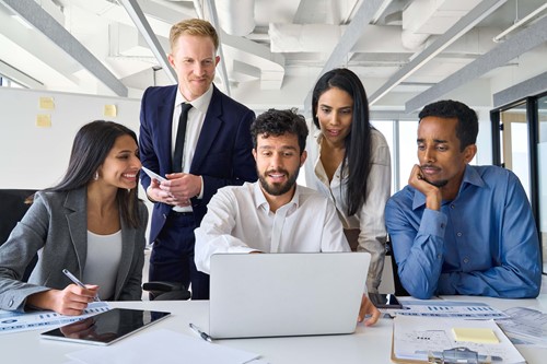 colleagues  gathered around one computer discussing 
