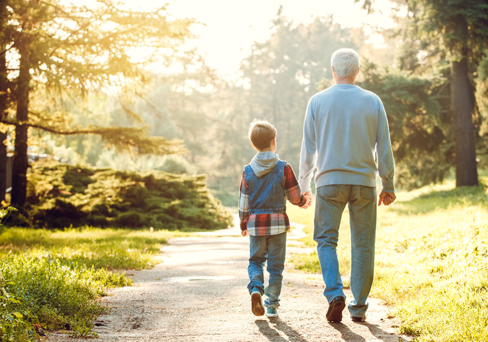 adult and child walking hand in hand in a sunny park 