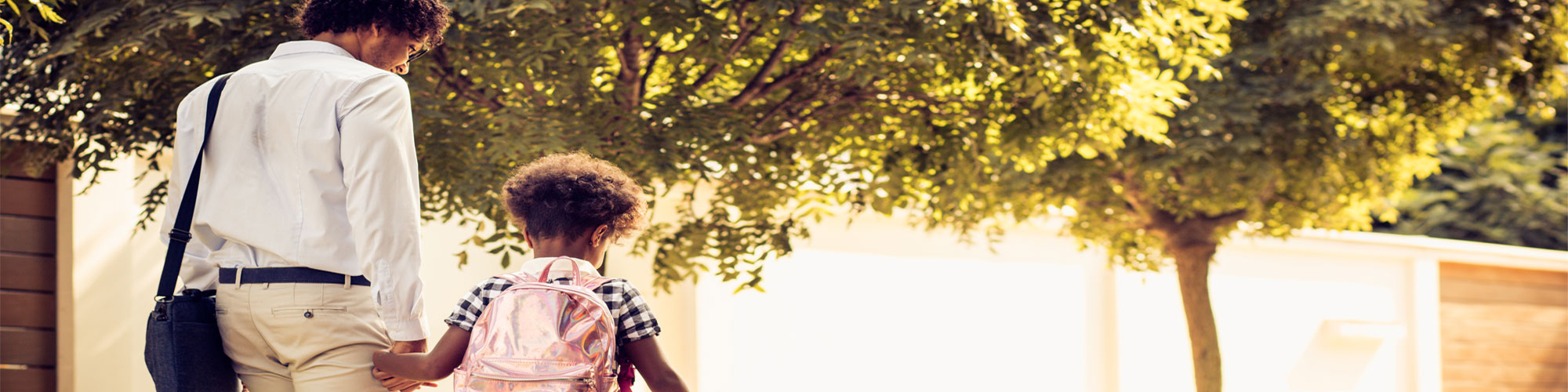 adult and child walking hand in hand in a sunny park 