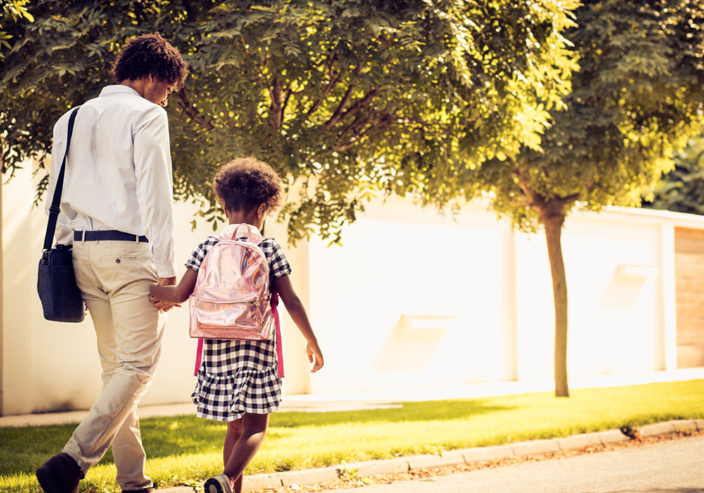 adult and child walking hand in hand in a sunny park 
