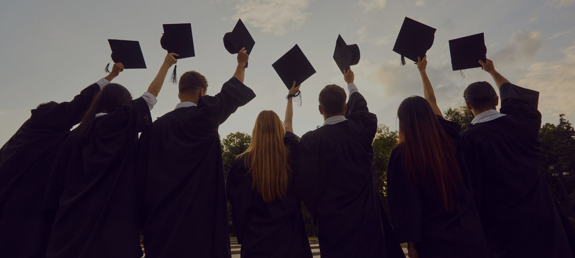 graduates holding up their caps