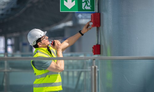 man talking into radio whilst checking fire alarm 